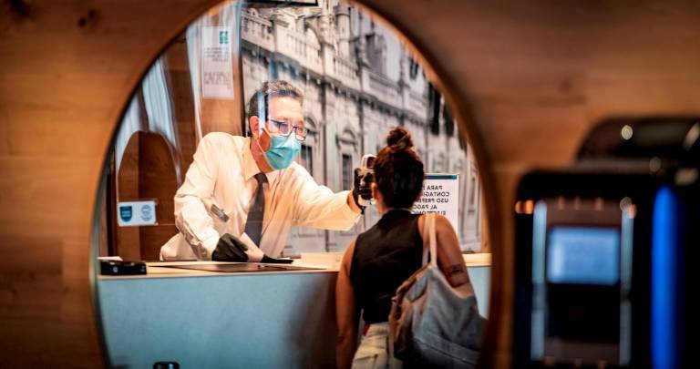 Un recepcionista de un hotel toma la temperatura a una huésped. FOTO: EFE