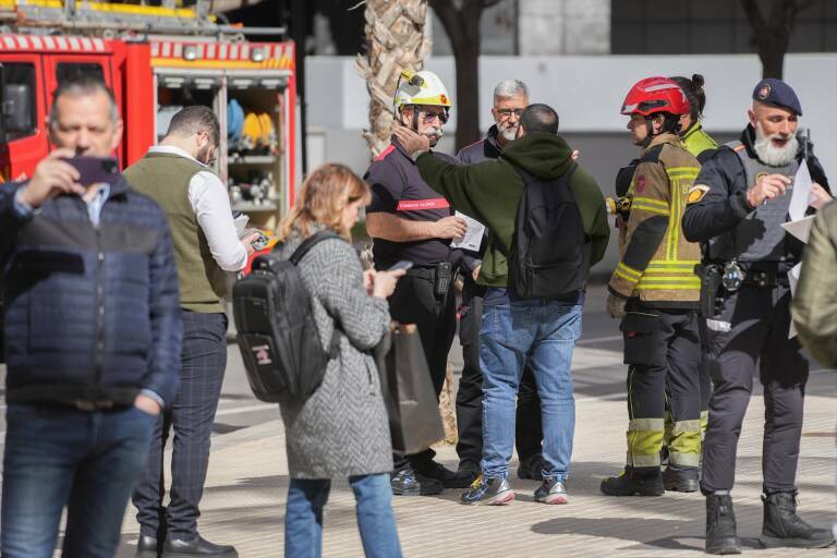 Bomberos con algunos de los afectados del incendio del edificio. Foto: JORGE GIL/EP