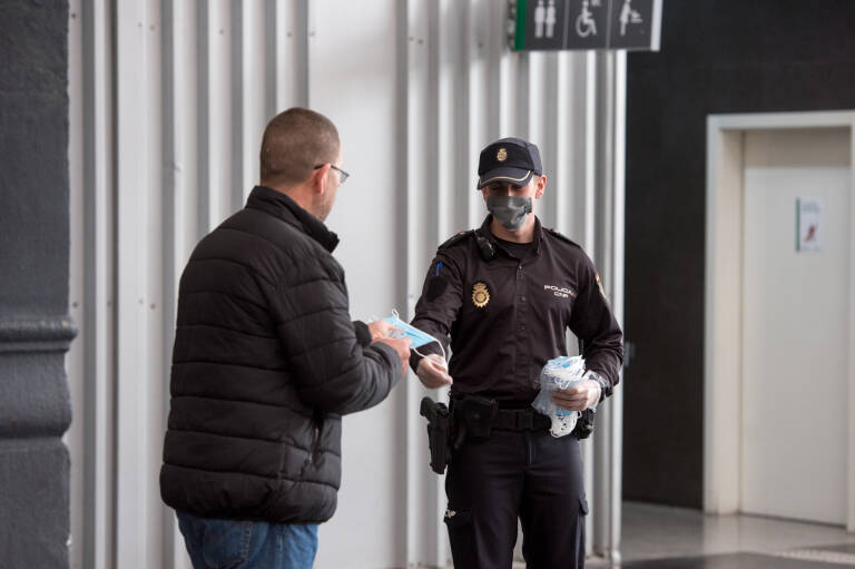 Un policía reparte mascarillas durante el confinamiento. Foto: RAFA MOLINA