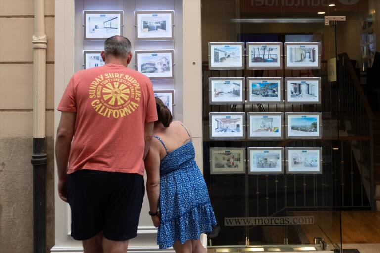 Dos personas observan los anuncios de viviendas en venta en una inmobiliaria. Foto: TOMÀS MOYÀ/EP